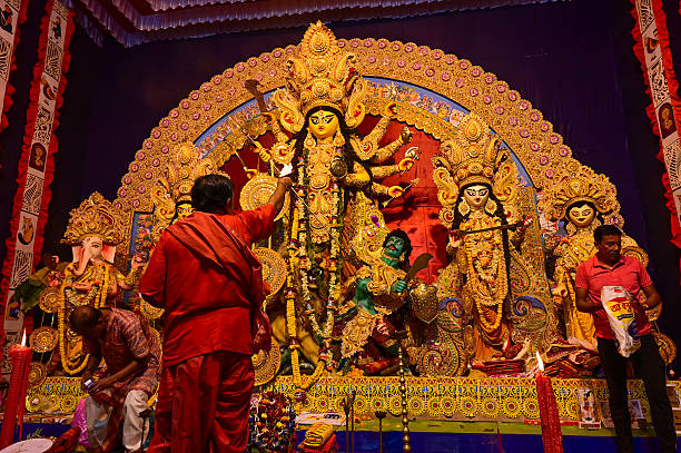 Howrah,West Bengal,India -11.10.2024 : Hindu purohit worshipping Goddess Durga with lit diya, pradip,, sacred holy lamp during nabami puja. Traditional Durga puja ritual. durga pooja
